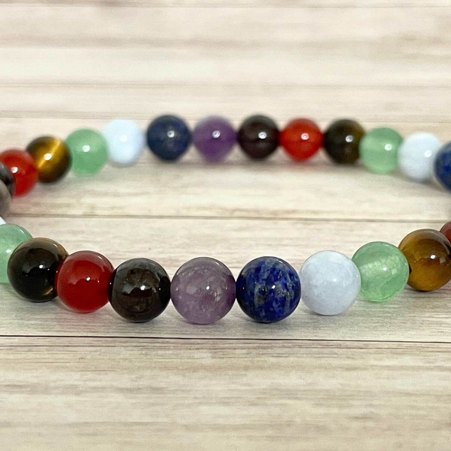 Gros plan des pierres du bracelet 7 chakras : grenat, cornaline, oeil de tigre, aventurine, aigue marine, lapis lazuli, améthyste