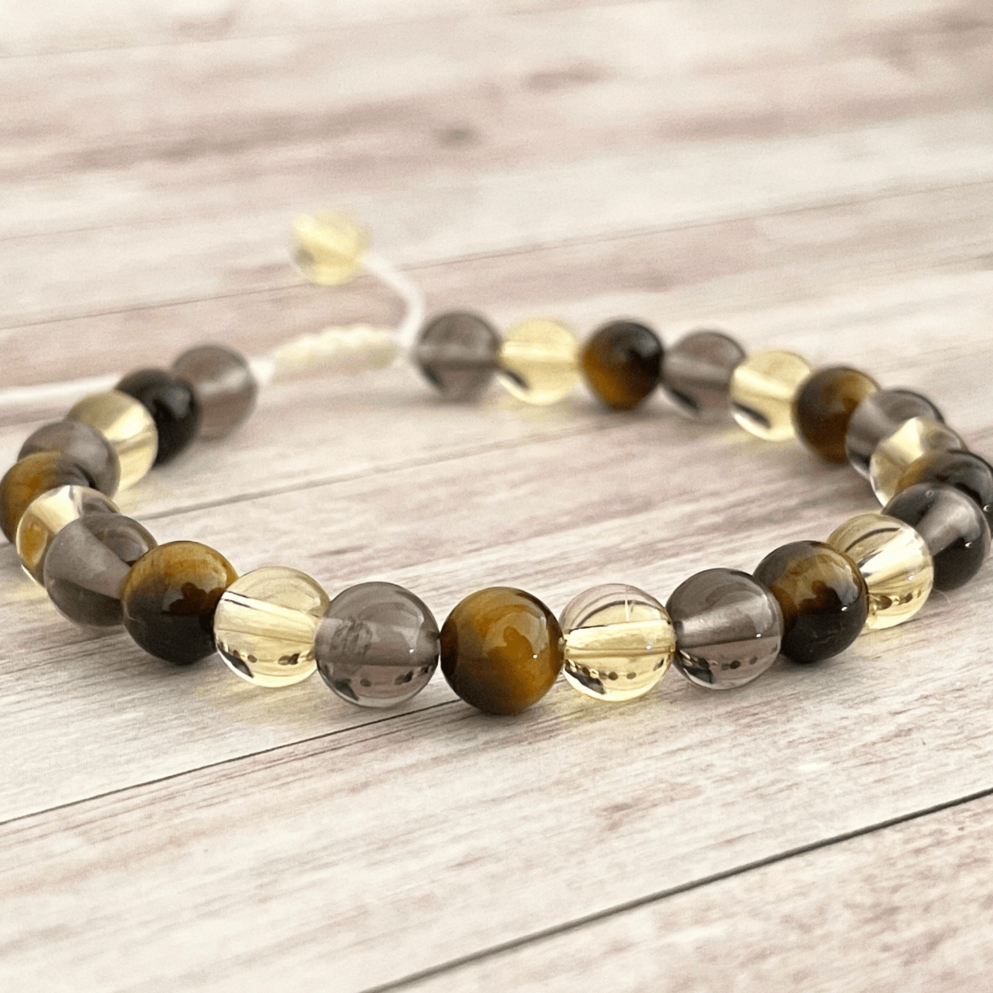 Gros plan sur les perles d’oeil de tigre, citrine et quartz fumé du bracelet