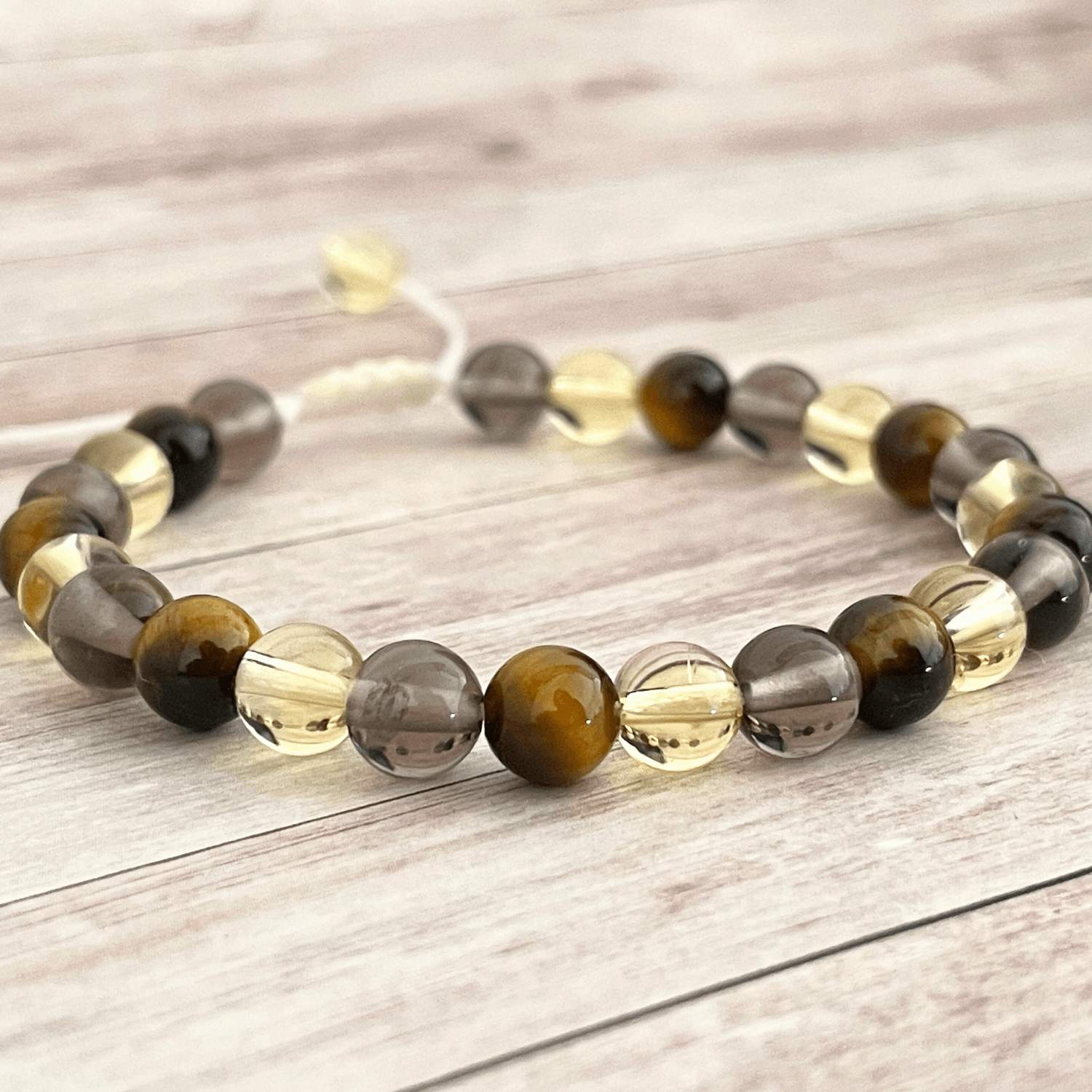 Gros plan sur les perles d’oeil de tigre, citrine et quartz fumé du bracelet