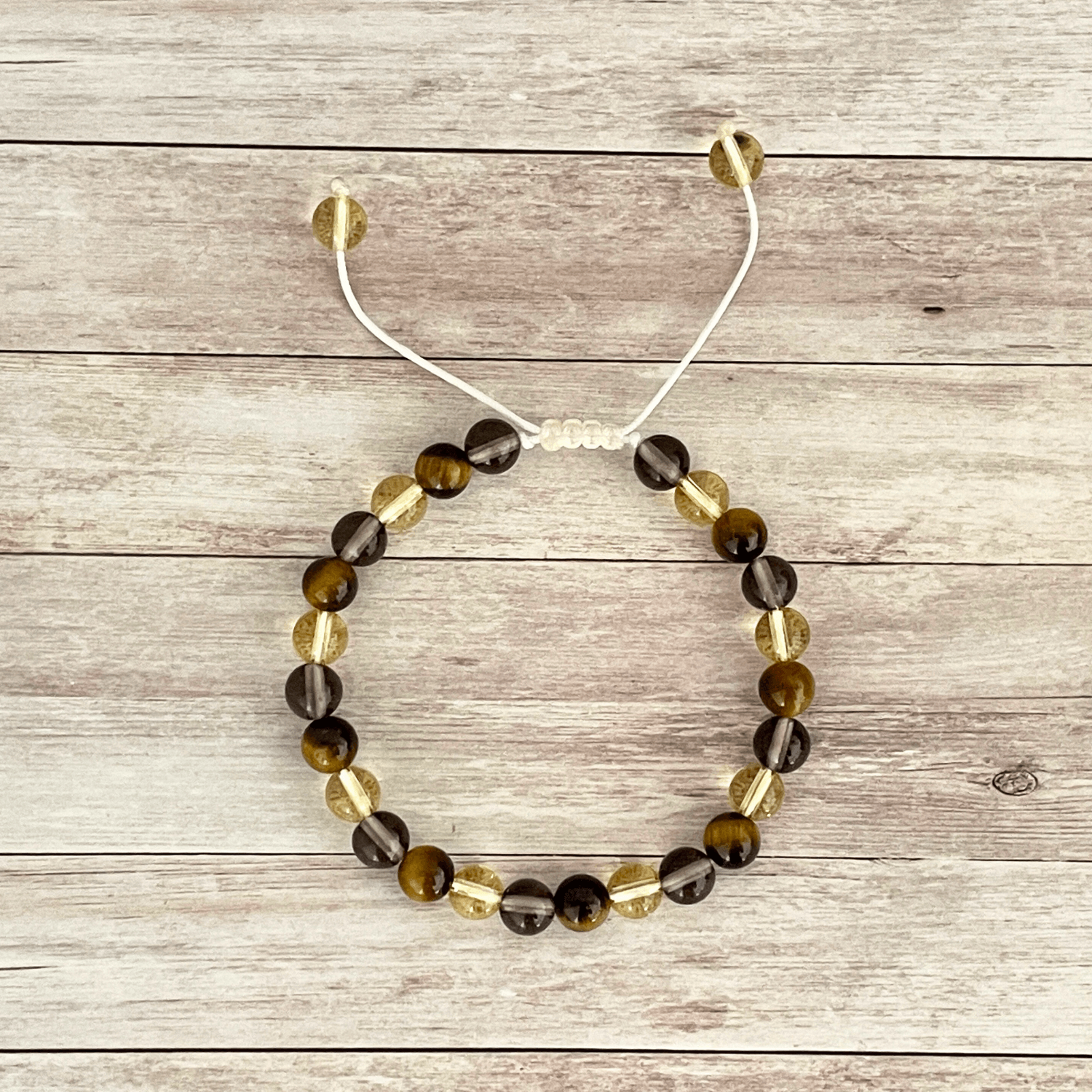 Vue de dessus du bracelet oeil de tigre, citrine et quartz fumé, perles alignées sur cordon