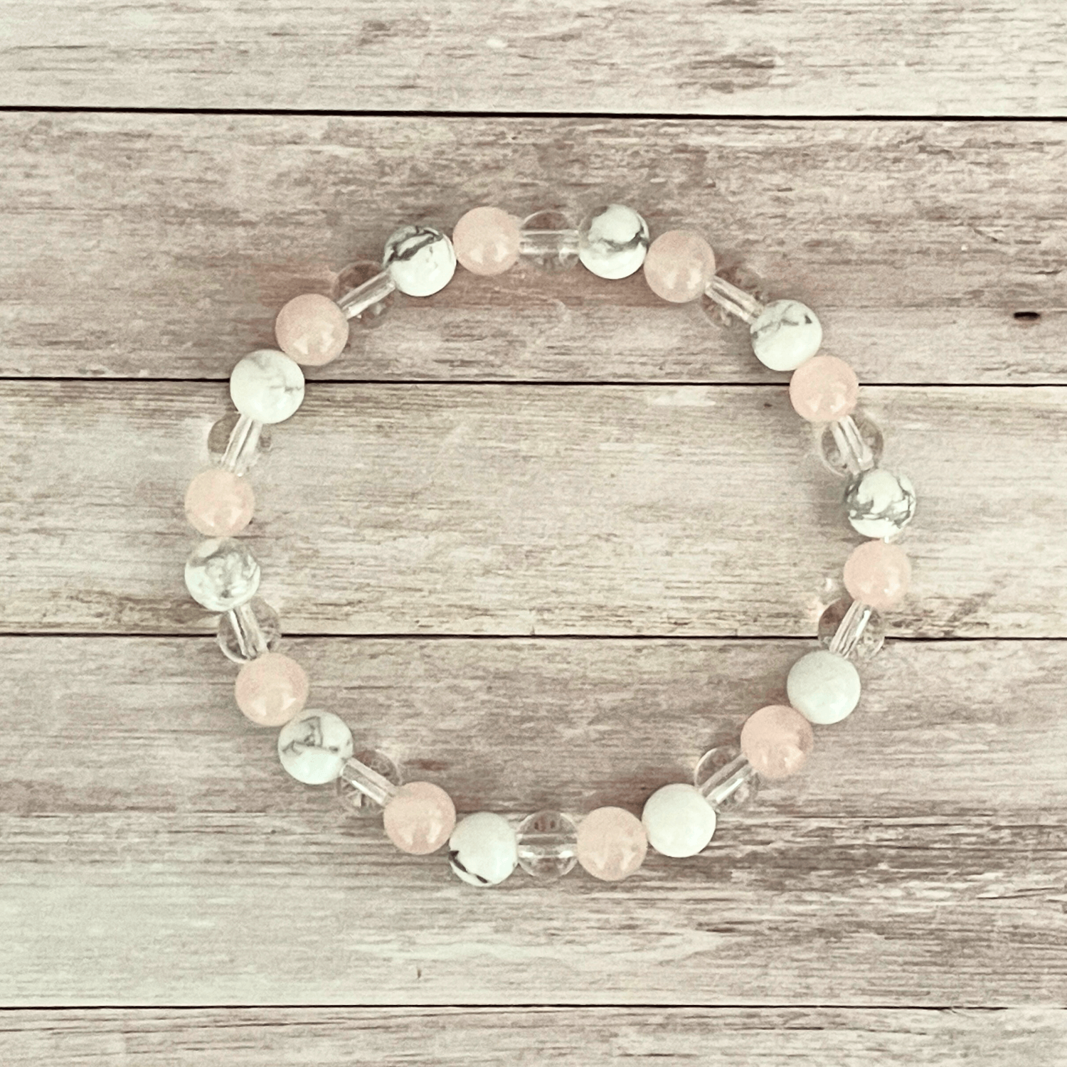 Vue de dessus du bracelet quartz rose, howlite et cristal de roche, perles alignées sur un fil élastique