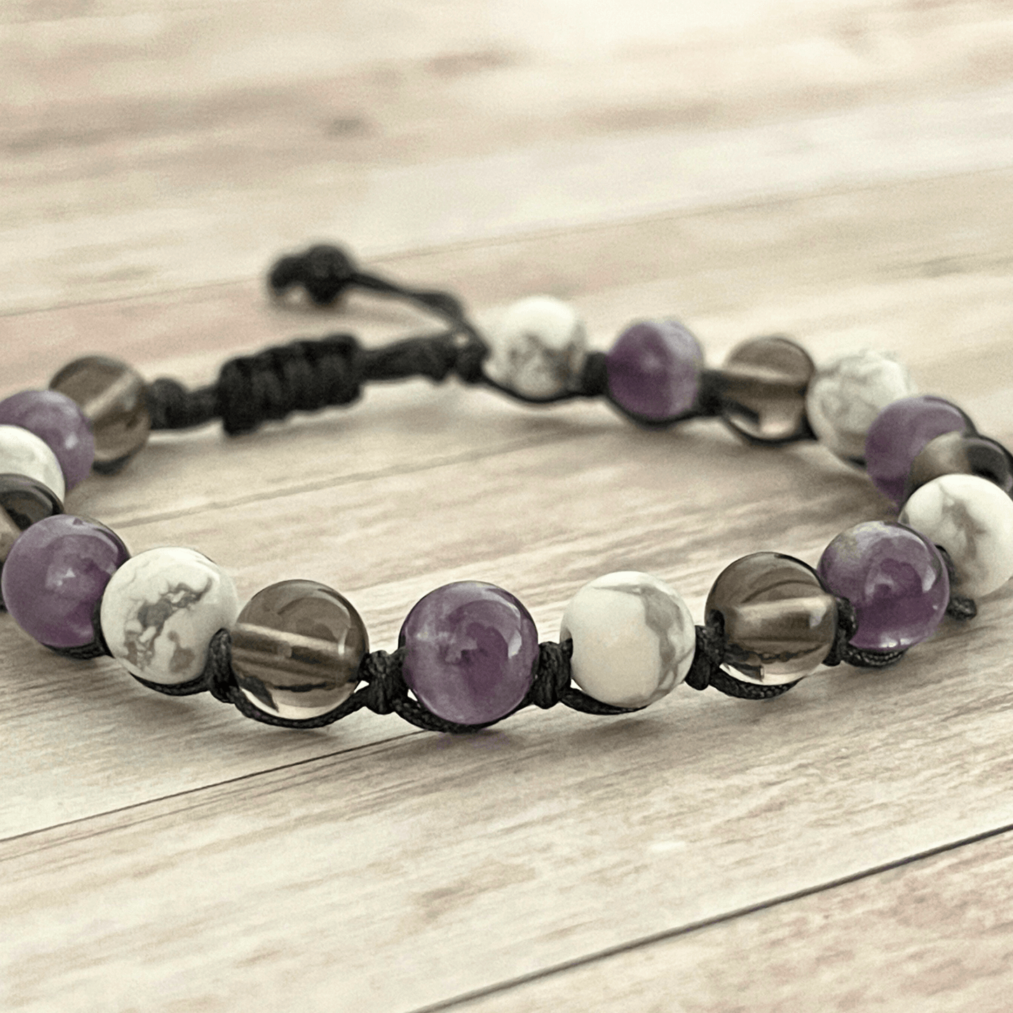 Gros plan sur les perles d’améthyste violette, howlite blanche et quartz fumé du bracelet