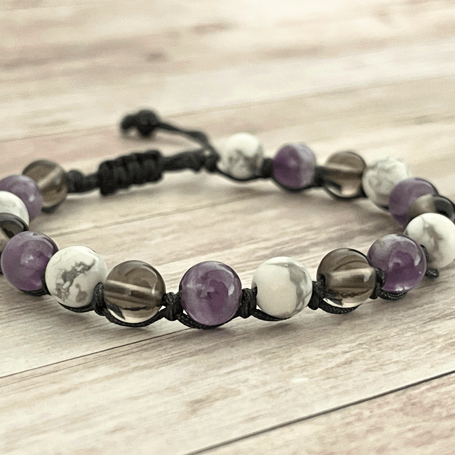 Gros plan sur les perles d’améthyste violette, howlite blanche et quartz fumé du bracelet