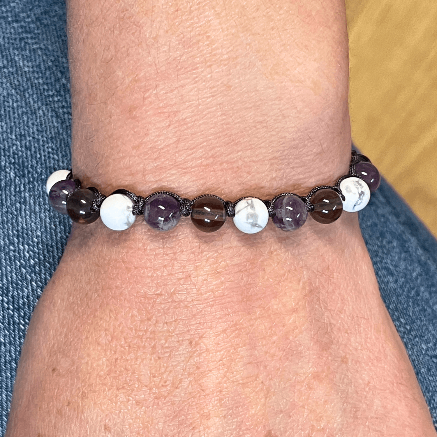 Bracelet améthyste, howlite et quartz fumé porté au poignet, cordon ajustable et perles en pierres naturelles