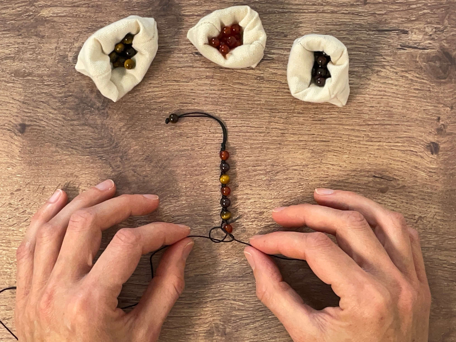 Tressage sur cordon ajustable d'un bracelet en pierres naturelles dans notre atelier situé en Auvergne (France).